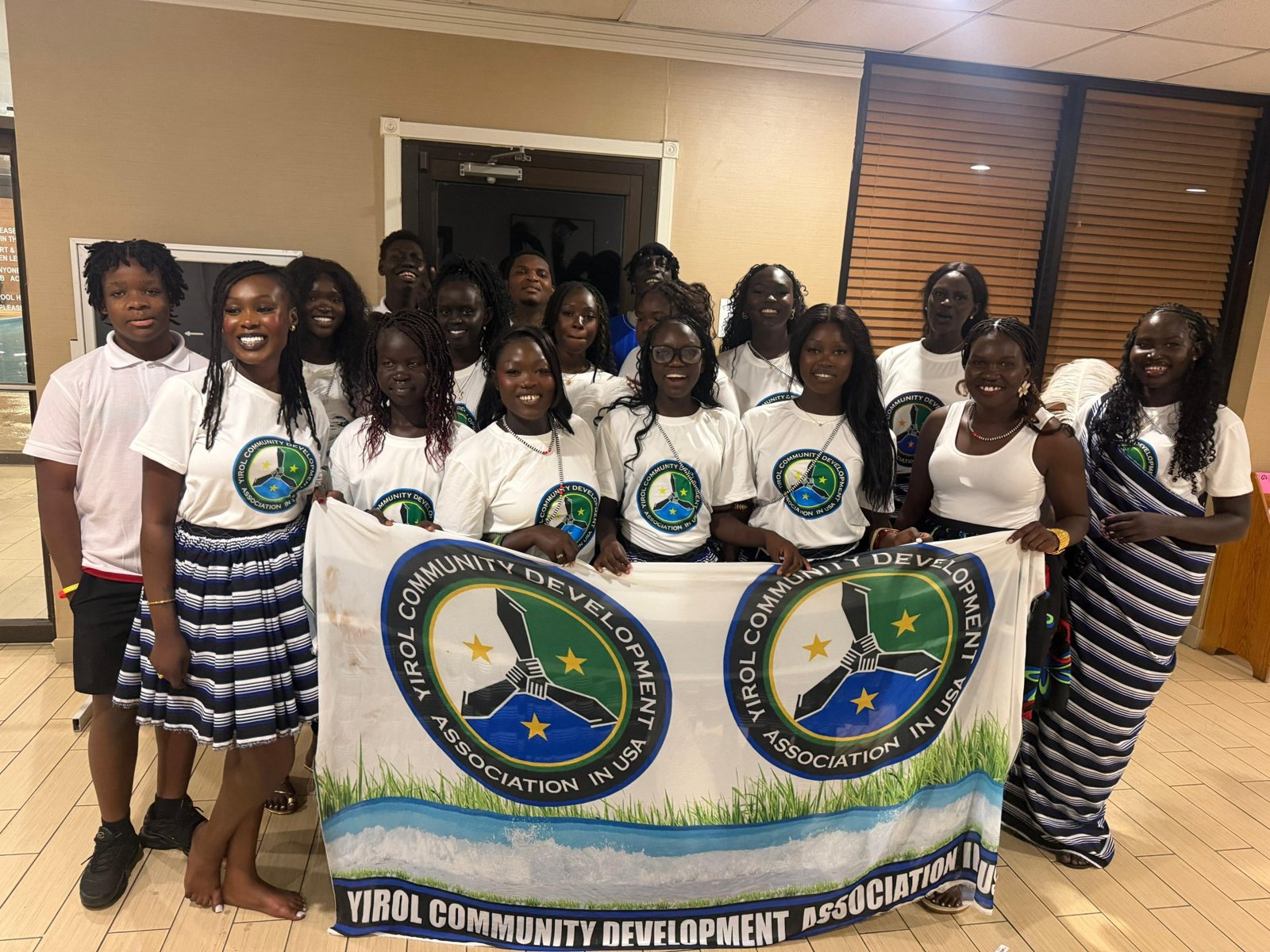 YCDA members in matching logo T-shirts and traditional dress, holding the Yirol Community Development Association banner